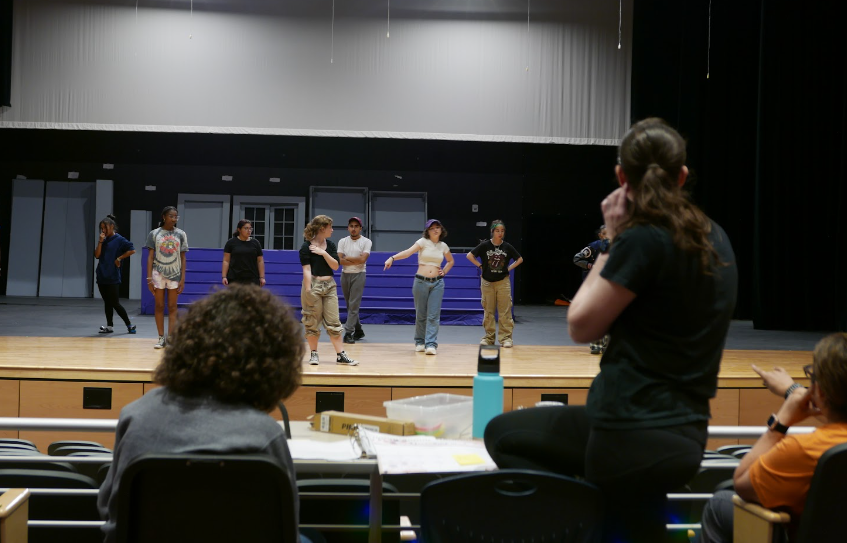 (From left to right) Senior John Parmley, Stage Manager, Head Director Rachel Gilmour, and Head Choreographer, Coach Harmony, from Canyon High School, watch the choreography of group number, ‘Don’t Lose Your Head’. Collaborating from the center of the auditorium, they converse and adjust the casts blocking.